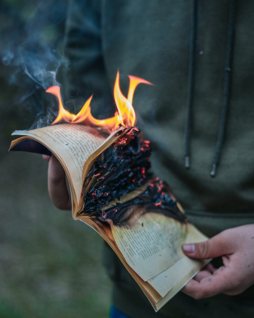 crop faceless man with burning book in hands
